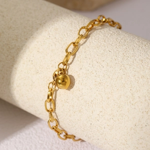 Detail of a polished gold geometric chain bracelet with round bead charm on display