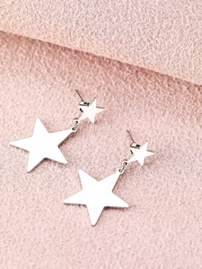 Close-up of silver star earrings featuring a dual star pendant on pink fabric background