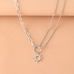 Polished silver stainless steel necklace with sun totem pendant on minimalist beige base