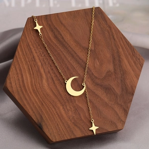 Macro detail of gold moon and star tassel necklace on hexagonal wooden display stand
