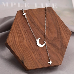 Detail view of crescent moon and star tassel necklace on a hexagonal wooden display