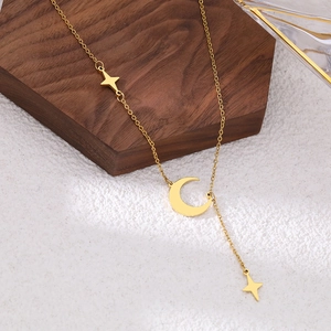 Gold stainless steel moon and star tassel necklace on a minimalist jewelry display