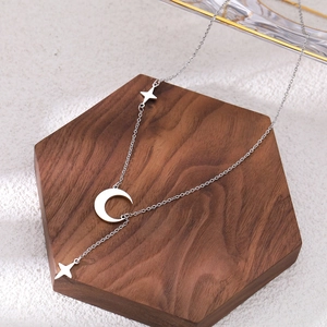 Macro detail of silver star and moon tassel pendant necklace on walnut wood display