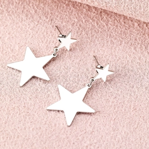 Silver star drop earrings with nested pentagram design on pink textured background