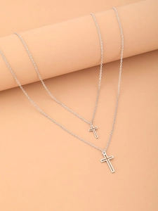 Close-up of double-layer silver cross pendants hanging on a minimalist cylinder display