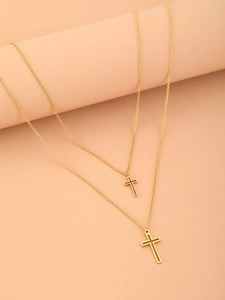 Detail shot of double-layered gold cross necklaces on aesthetic pink cylinder props