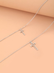 Close-up of double-layered silver cross necklaces on minimalist display stand