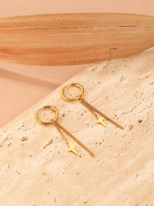 Detail of 18k gold plated star pendant earrings on a natural stone surface