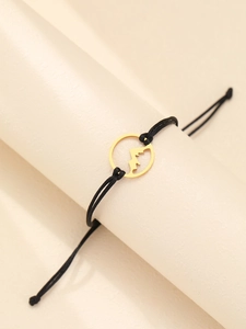 Detailed shot of golden mountain peak charm on adjustable black braided rope bracelet