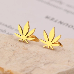 Elegant gold maple leaf stud earrings on stone background for women's fashion