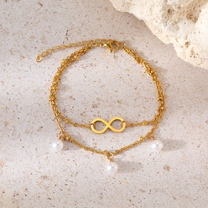 Detail of gold-plated infinity symbol and white pearls on double-layer stainless steel anklet
