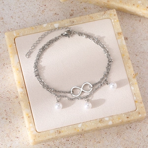 Detail of double-layer stainless steel anklet with infinity symbol and three pearls