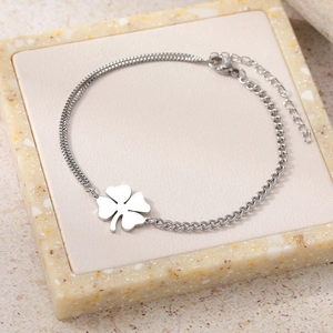 Detail of silver clover charm bracelet with asymmetric chain on stone display