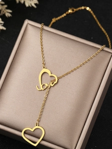 Detailed view of a gold Y-shaped double heart necklace featuring love script engraving