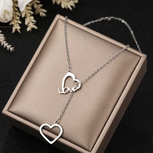 Detail of silver double heart pendant necklace with love engraving on a jewelry box