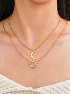Detail of layered gold titanium steel necklace with crescent moon and sunburst pendants
