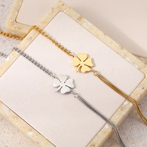 Fashionable four-leaf clover bracelets in gold and silver steel on a stone pedestal