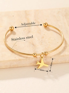 Detail of adjustable stainless steel bangle with gold beads and plane charm on stone base