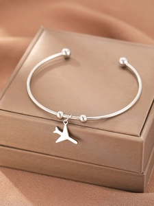 Detailed close-up of a silver airplane charm on a stainless steel open cuff bracelet