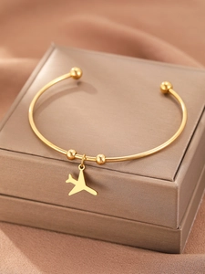 Detail of minimalist gold-plated stainless steel bracelet featuring a small airplane charm