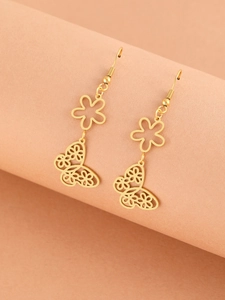 Detailed macro view of gold-tone hollow butterfly earrings with floral filigree design