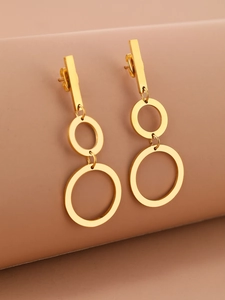 Macro view of gold-plated stainless steel triple hoop drop earrings on a brown stand