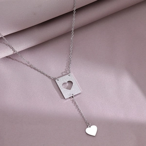 Chic heart pendant necklace in silver finish on pink silk background for a stylish look