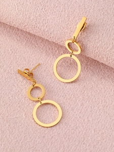Detailed view of layered golden geometric hoop earrings on light pink textured background