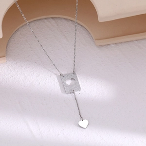 Detail of silver Y-shaped necklace with frosted heart cutout pendant and small heart drop