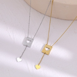 Minimalist gold and silver heart pendant necklaces displayed on a marble base