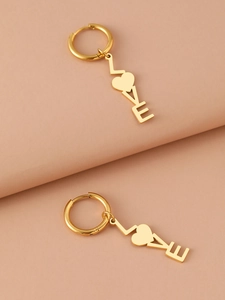 Detailansicht der goldenen LOVE-Ohrringe mit herzförmigem O auf elegantem rosa Hintergrund