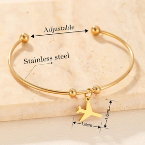 Minimalist adjustable gold stainless steel bangle with a polished airplane pendant charm