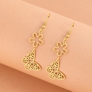 Elegant gold hollow butterfly and flower drop earrings displayed on a pink curved stand