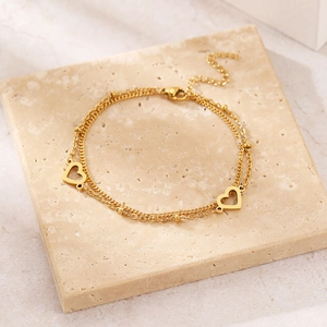 Dettaglio ravvicinato di un bracciale dorato a doppio strato con cuori su pietra naturale