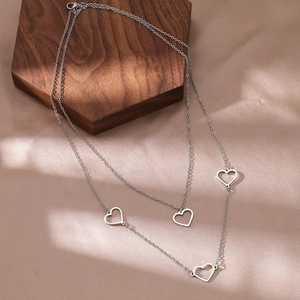 Detail of silver double-layer necklace with hollow heart pendants on wooden display