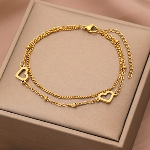 Dettaglio del bracciale a cuore a doppio strato dorato su elegante confezione di seta
