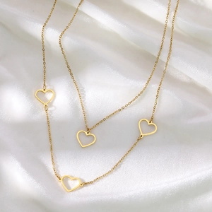 Detail of elegant gold necklace featuring four hollow heart pendants on a silk background