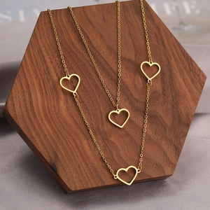 Elegant gold hollow heart pendant necklace displayed on a luxury wooden jewelry stand