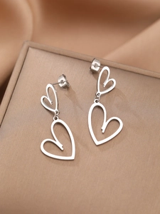 Détail de boucles d'oreilles double cœur en argent sur satin couleur champagne