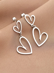 Détail des boucles d'oreilles cœur en argent avec double breloque sur tissu satiné doux