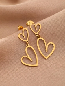 Détail macro de boucles d'oreilles double cœur en acier doré sur tissu en soie