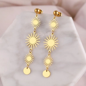 Golden stainless steel long tassel sunburst drop earrings on marble display stand