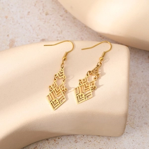 Detail of geometric hollow layered gold drop earrings on a minimalist beige background