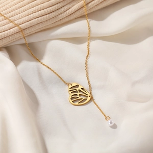 Close-up of golden butterfly heart pendant and pearl detail on soft silk fabric