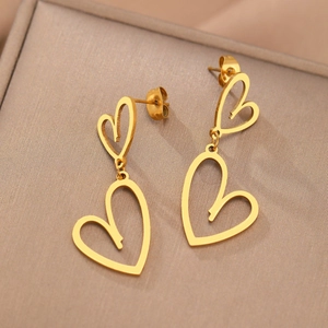 Boucles d'oreilles pendantes cœurs évidés dorés sur un écrin de bijoux en velours