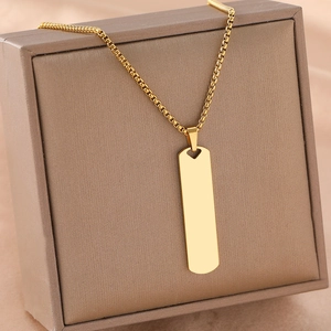 Gold rectangular bar necklace with heart cutout and box chain on brown leather box