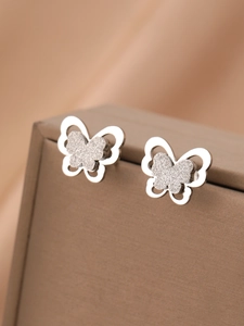 Gros plan de boucles d'oreilles papillon en argent avec des ailes mates sur l'écrin