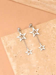 Détail de boucles d'oreilles étoiles en acier inoxydable sur fond de marbre texturé