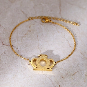 Bracelet élégant en or avec pendentif couronne mat sur fond de marbre