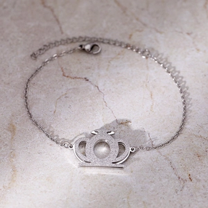 Bracelet argenté avec pendentif couronne scintillante et fermoir réglable sur marbre
